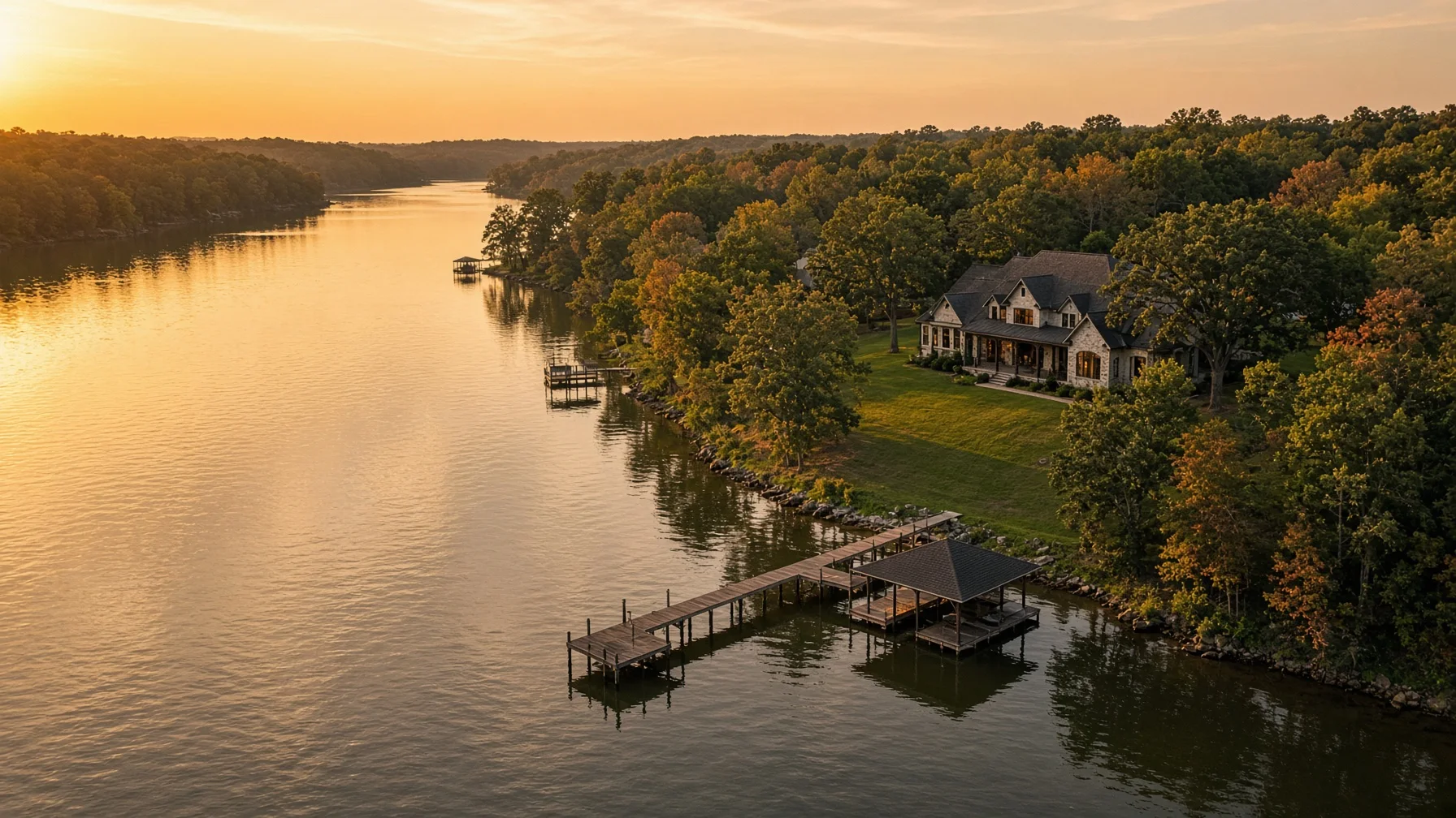 Aerial view of a waterfront home, dock, shoreline, and surrounding water.